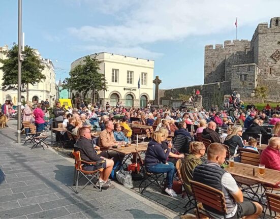 Football fans watching game outdoors on big screen,