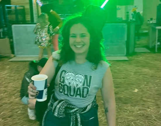 Mae Challis at Glastonbury wearing a grey shirt that reads "Goon Squad'